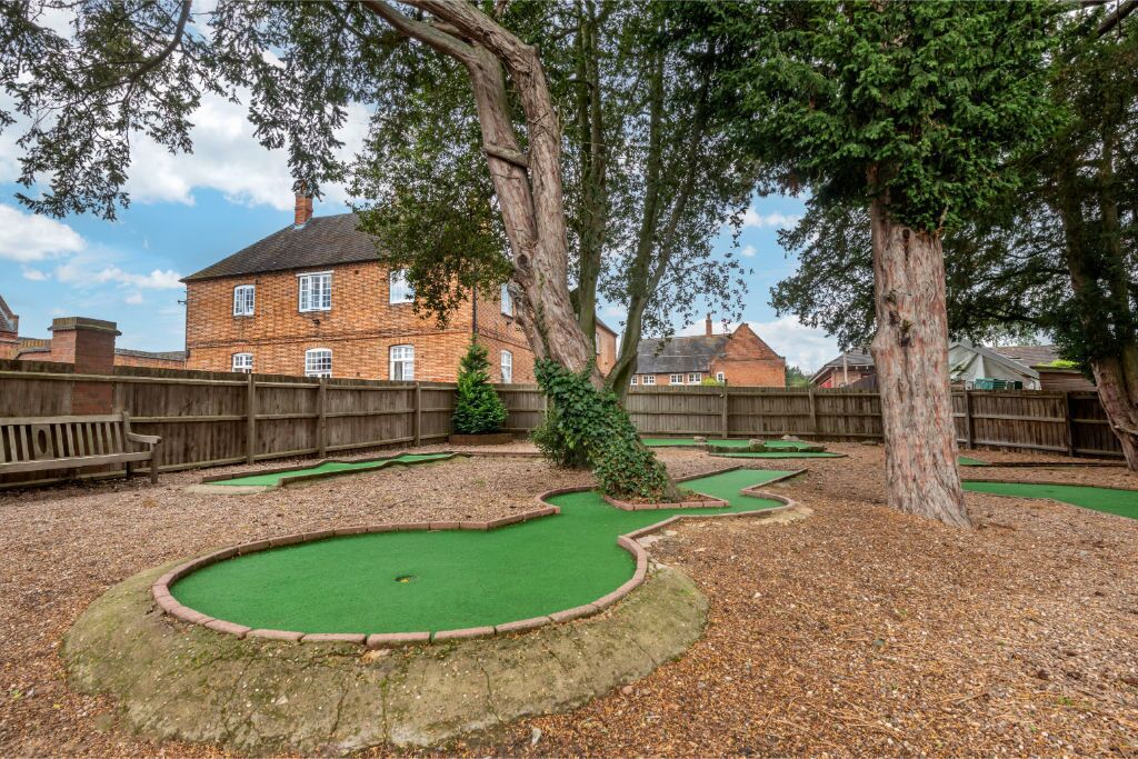 Um campo de mini golfe com um edifício de tijolos ao fundo.