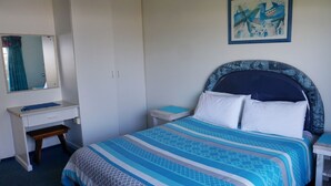 A bedroom with a bed, a desk, a chair, a wardrobe, and a painting on the wall. - Southern Comfort - On the Rocks (Margate)