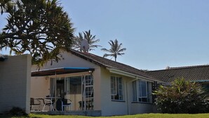 A single-story house with a covered patio, a small lawn, and a palm tree in the background. - Southern Comfort - On the Rocks (Margate)