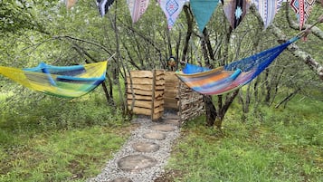 A wooden structure with a thatched roof, surrounded by a gravel path and colorful triangular flags.