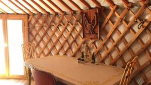 A dining area with a round table, chairs, and a wooden lattice ceiling.
