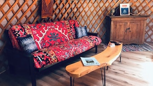A room with a patterned sofa, a wooden bench, a cabinet, and a framed picture on the wall.