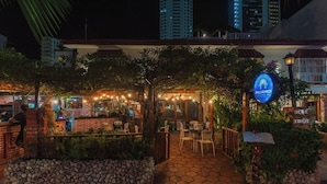 An outdoor restaurant with a brick facade, string lights, and outdoor seating. - Baluarte Cartagena Hotel Boutique (Cartagena)
