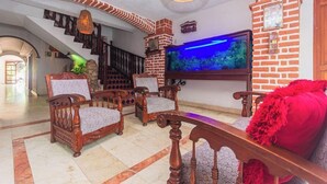 A living room with a brick fireplace, a large flat-screen TV, and a staircase leading to another level. - Baluarte Cartagena Hotel Boutique (Cartagena)