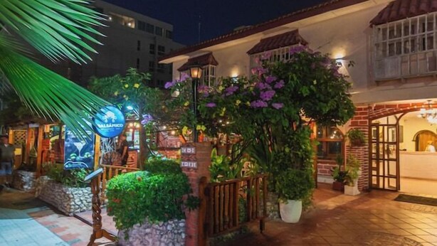 A courtyard with a brick pathway, potted plants, and a building entrance. - Baluarte Cartagena Hotel Boutique (Cartagena)