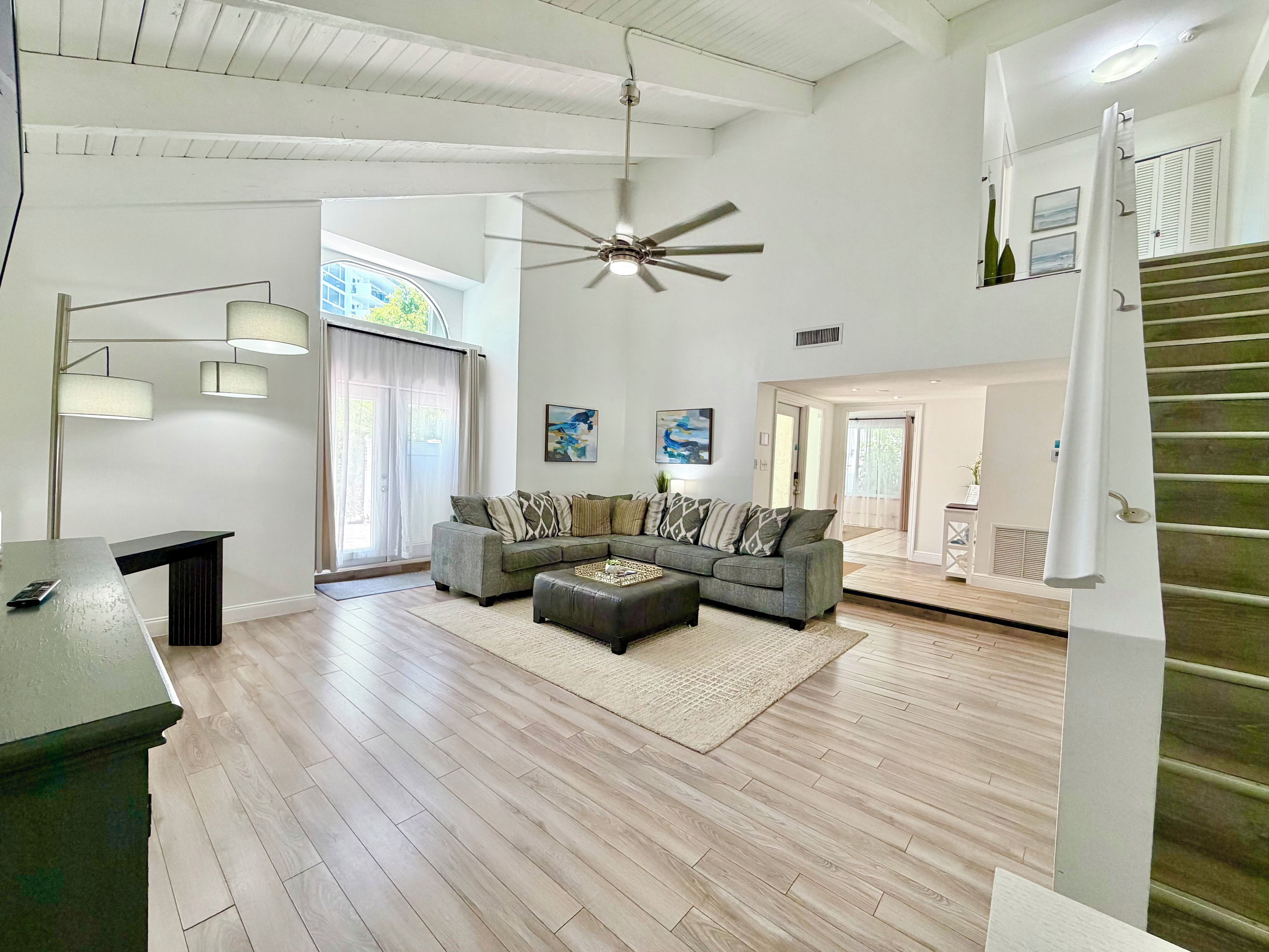 A spacious living area with a ceiling fan, a sofa set, and a dining table.