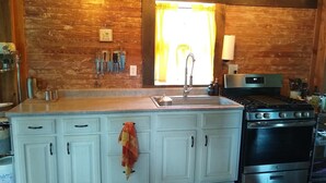 Cucina con mobili bianchi, un fornello e un lavello.