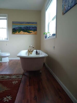 A bathroom with a clawfoot bathtub, a toilet, and a painting on the wall. - Heydt Homestead (Seneca Rocks)