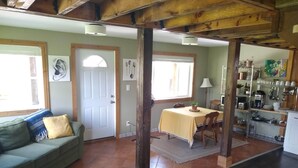 Un accogliente soggiorno con divano, tavolo da pranzo e angolo cottura con scaffali ed elettrodomestici.
