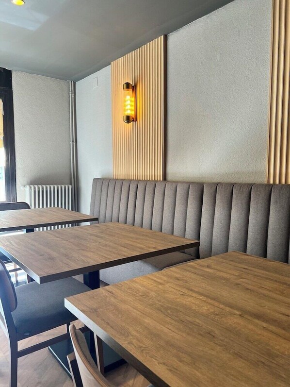 A modern interior with wooden tables and grey upholstered booths. - Hotel Paris (Encamp)