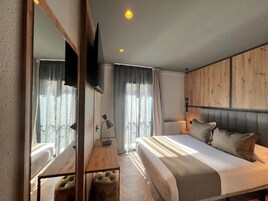 Un dormitorio moderno con una cama grande, un televisor de pantalla plana montado en la pared y un cabecero de madera.