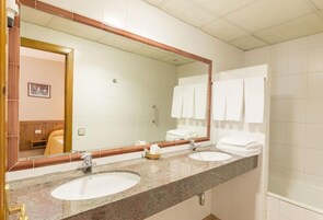 Un baño con dos lavamanos, un espejo grande y un perchero para toallas.
