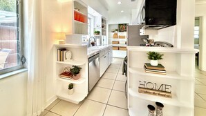A modern kitchen with white cabinetry, a built-in oven, and a flat-screen TV mounted above the counter.