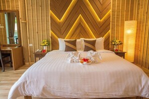 A hotel room with a large bed, wooden panel walls, and a mirror. - Adarin Beach Resort (Koh Samui)