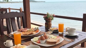 A breakfast table with various dishes, drinks, and a view of the sea. - Adarin Beach Resort (Koh Samui)