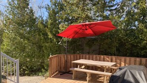 A wooden deck with a picnic table and a red umbrella.