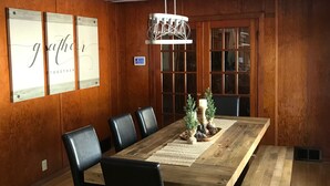 A conference room with a long wooden table, black chairs, a chandelier, and wooden paneled walls. - Super Spacious Lakehome (Richmond)
