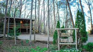 A rustic cabin with a wooden deck and a signpost indicating nearby attractions like beer and deer. - Oh Deer - Studio Wooded Twin Cabin, Hot Tub, TV & Wifi (Sevierville)