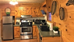 A kitchen with wooden cabinets, a stainless steel refrigerator, an oven, a microwave, and a sink. - Oh Deer - Studio Wooded Twin Cabin, Hot Tub, TV & Wifi (Sevierville)