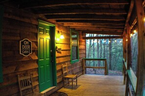 Relax on the porch with a bench and table, surrounded by a secluded wooded area.