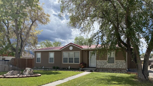 Una casa residencial con techo rojo, paredes exteriores color beige y un muro de acento de piedra.