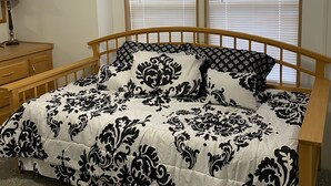 Un dormitorio con una cama de madera, una mesita de noche, una lámpara y una ventana con persianas.