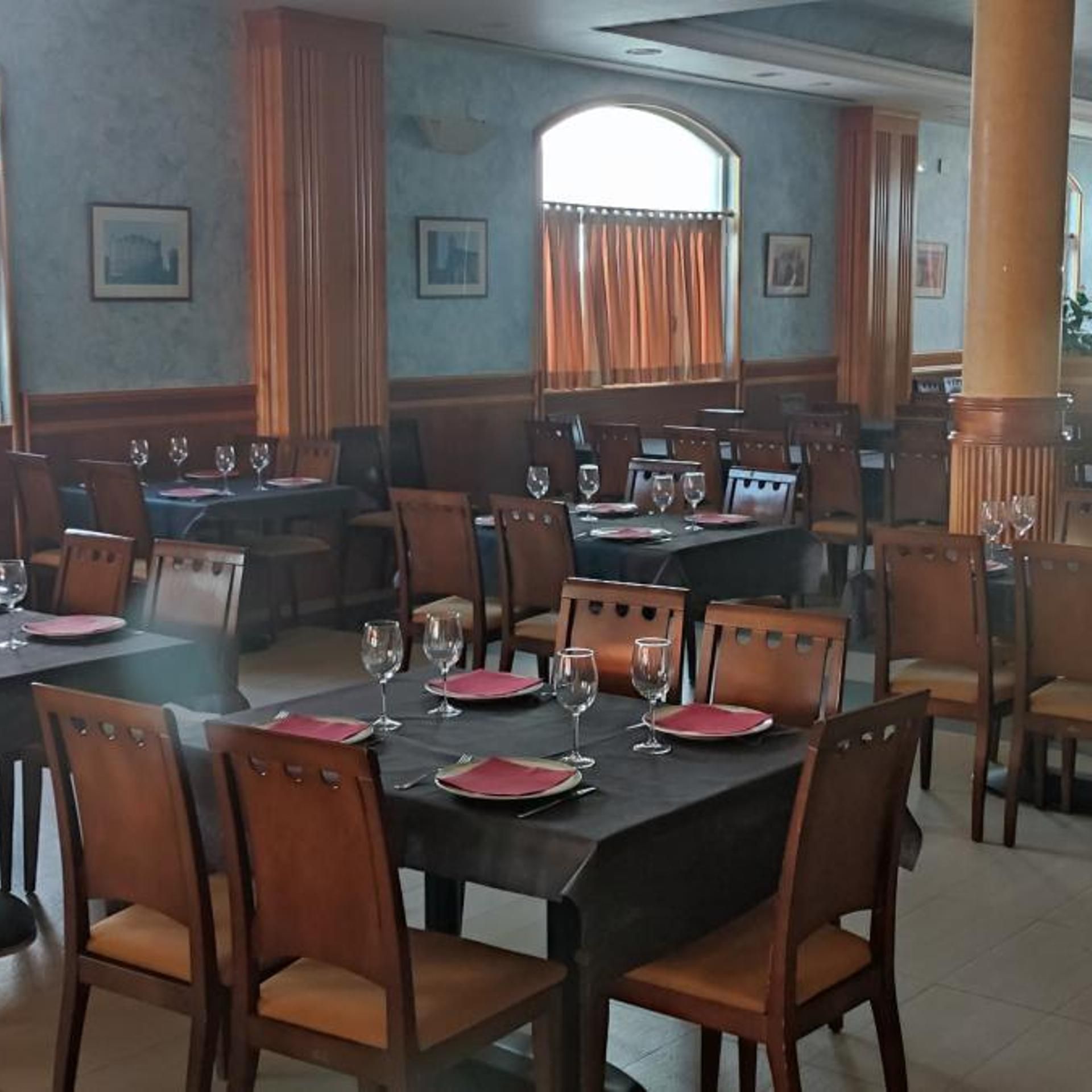 A dining area with tables set for a meal, featuring chairs and wine glasses.