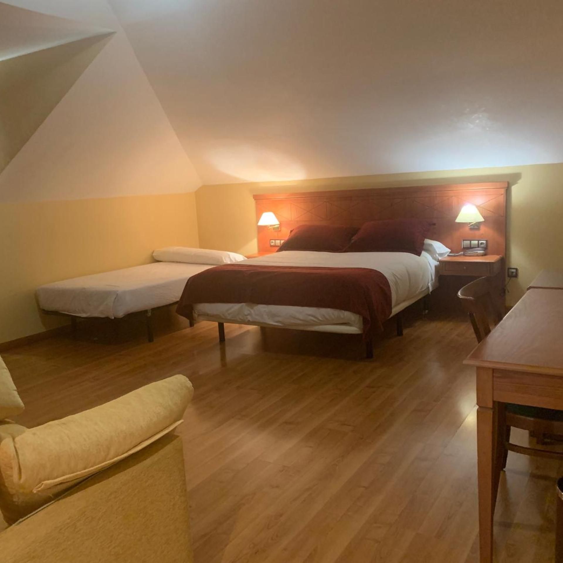 A room with two beds, a wooden table, and a chair.