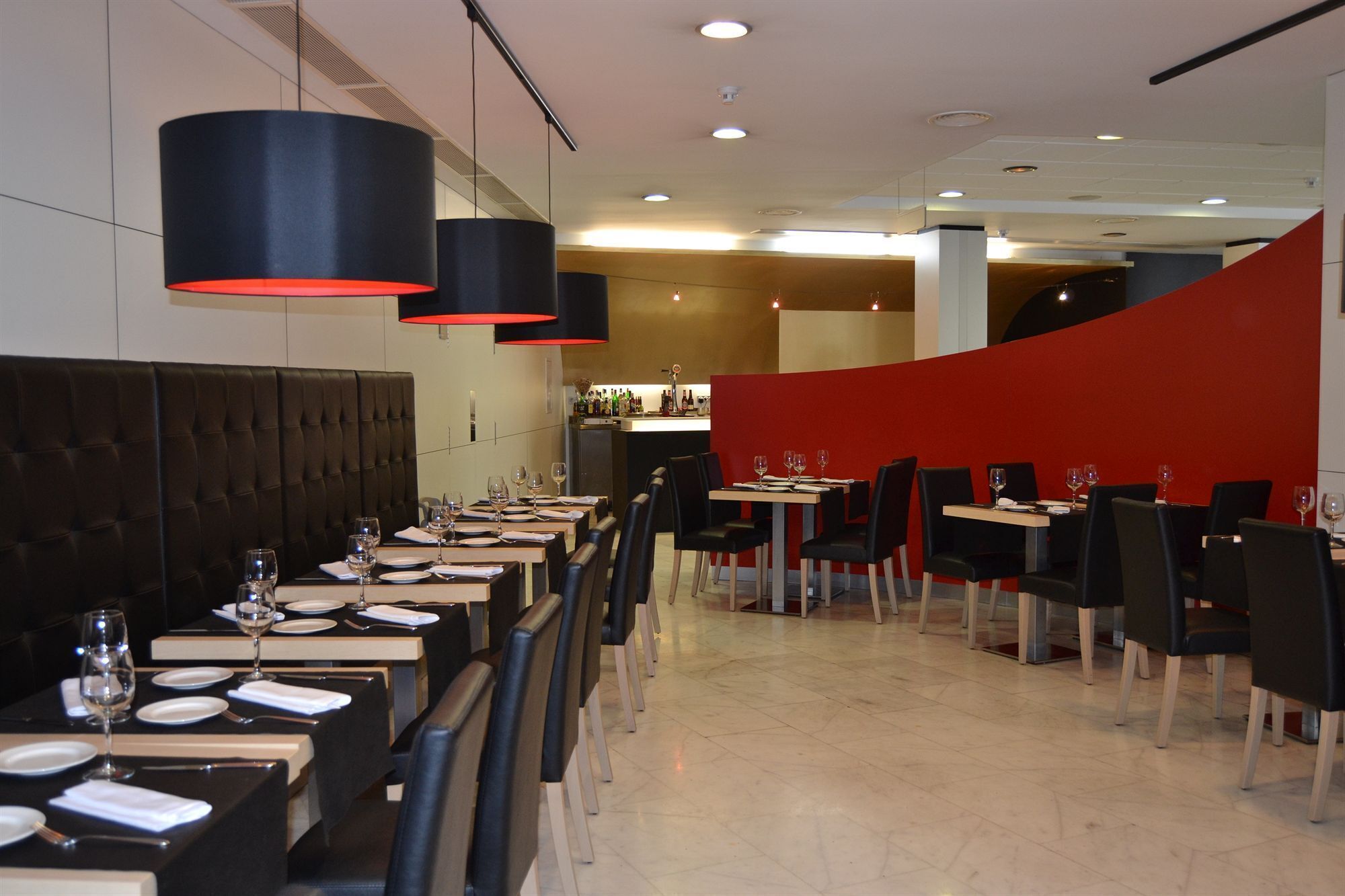 Un restaurant avec de nombreuses tables, des chaises noires et des murs d’un rouge vif.