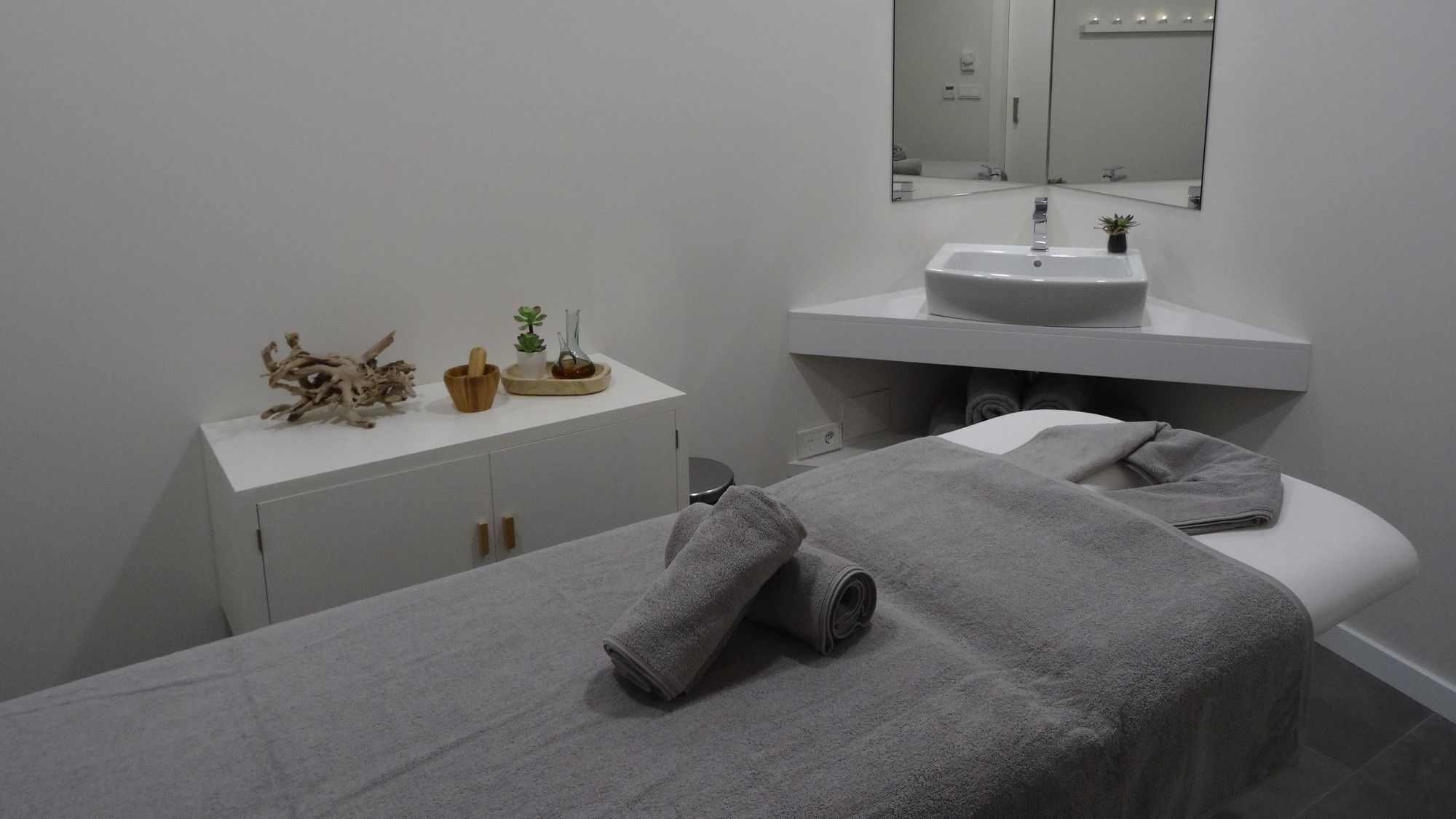 Un baño moderno con un tocador blanco, un espejo grande y una toalla en el suelo.