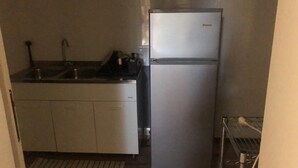 Une cuisine de taille réduite, équipée d’un évier, d’une cuisinière et d’un réfrigérateur.