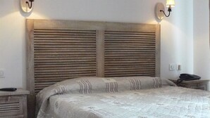 A bedroom with a wooden headboard, two bedside tables, a bed with a patterned quilt, and wall-mounted lamps. - Kyriad Nuits-saint-georges (Nuits-Saint-Georges)