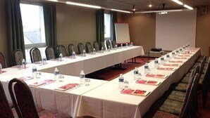 A conference room with a long table, chairs, and a projector screen. - Kyriad Nuits-saint-georges (Nuits-Saint-Georges)