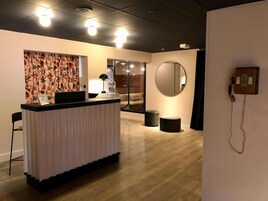 Una zona de recepción con mostrador, un espejo grande y un teléfono.