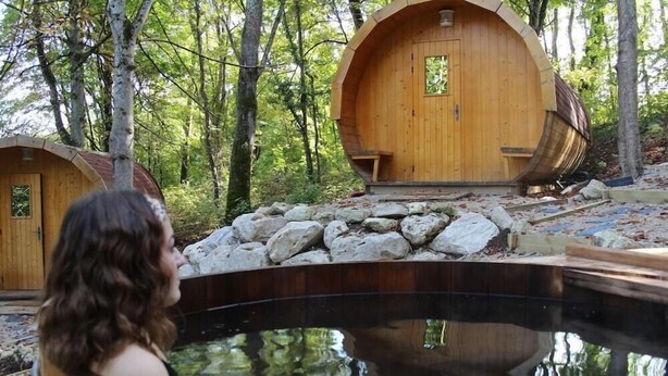 Een houten blokhut met een rond ontwerp, een jacuzzi en een pad van stenen.