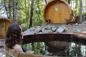 A wooden cabin with a circular design, a hot tub, and a stone pathway. - Hotel the Originals Domaine Des Thomeaux (Mosnes)