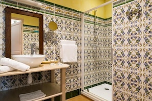A bathroom with a sink, mirror, and shower.