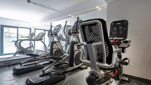 Un gimnasio con cintas de correr, elípticas y una bicicleta estática.
