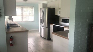 A compact kitchen with a refrigerator, stove, and sink. - Weeki Wachee MAIN RIVER (Spring Hill)
