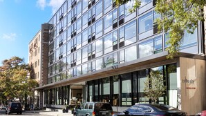 En moderne bygning med store vinduer og en murstensfacade, samt et skilt med teksten 'Study Heirloom'.