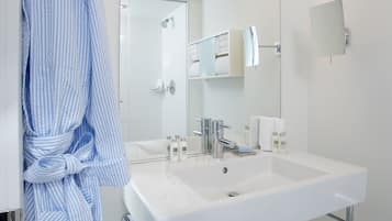 Un baño moderno con un lavabo grande, accesorios cromados y una bata colgada en la puerta.