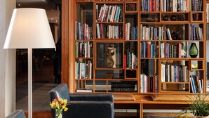 Et bibliotek med bogreoler, sofa, lampe og pynteting.