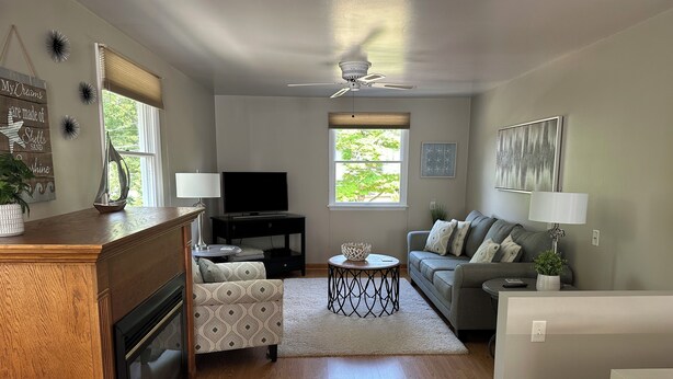 A living room with a wooden coffee table, a gray sofa, a TV, and a ceiling fan. - Located in the heart of Downtown Saugatuck (Saugatuck)