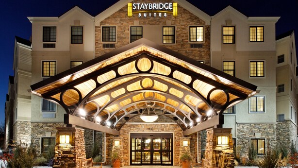 A hotel entrance with a stone facade, a covered patio area, and a well-lit entrance.