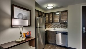 A modern kitchen with stainless steel appliances, a tiled backsplash, and wooden cabinets.