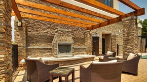 A stone exterior with a fireplace, wicker furniture, and a pergola.