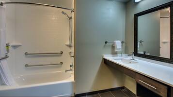 A bathroom with a bathtub, a sink, a mirror, and a towel rack.