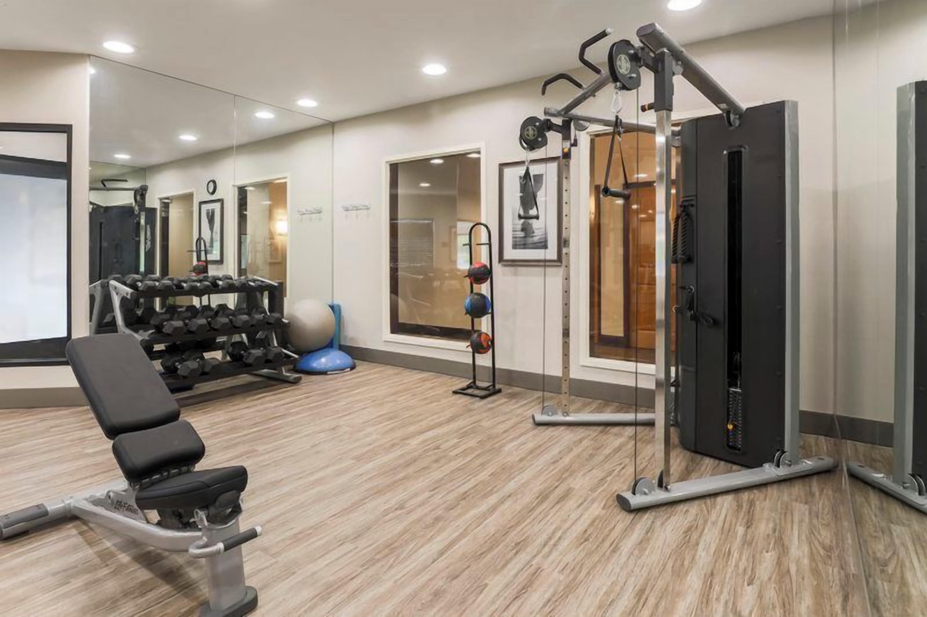 Un gimnasio con equipo de ejercicio, una banca y un espejo.