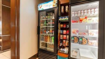 A vending machine with various beverages and snacks, and a refrigerated display case with packaged food items.