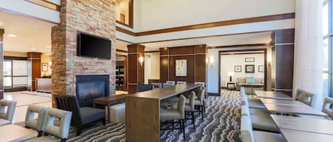 A hotel lobby with a fireplace, seating area, and a conference table.